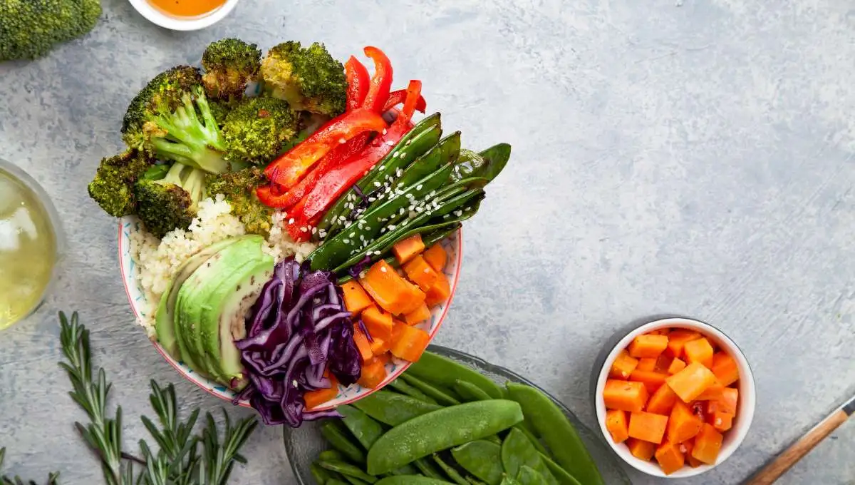 Tasty healthy bowl for lunch with couscous, baked broccoli and carrots cut in cubes, fried peas, avocados and red cabbage. Easy vegetarian diet concept. Rustic background, copy space.